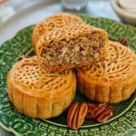 Galettes de mooncake et noix de pécan sur une assiette verte décorative, gâteau chinois traditionnel avec garniture de noix, pâtisserie sucrée asiatique, dessert pour célébrations, recette artisanale.
