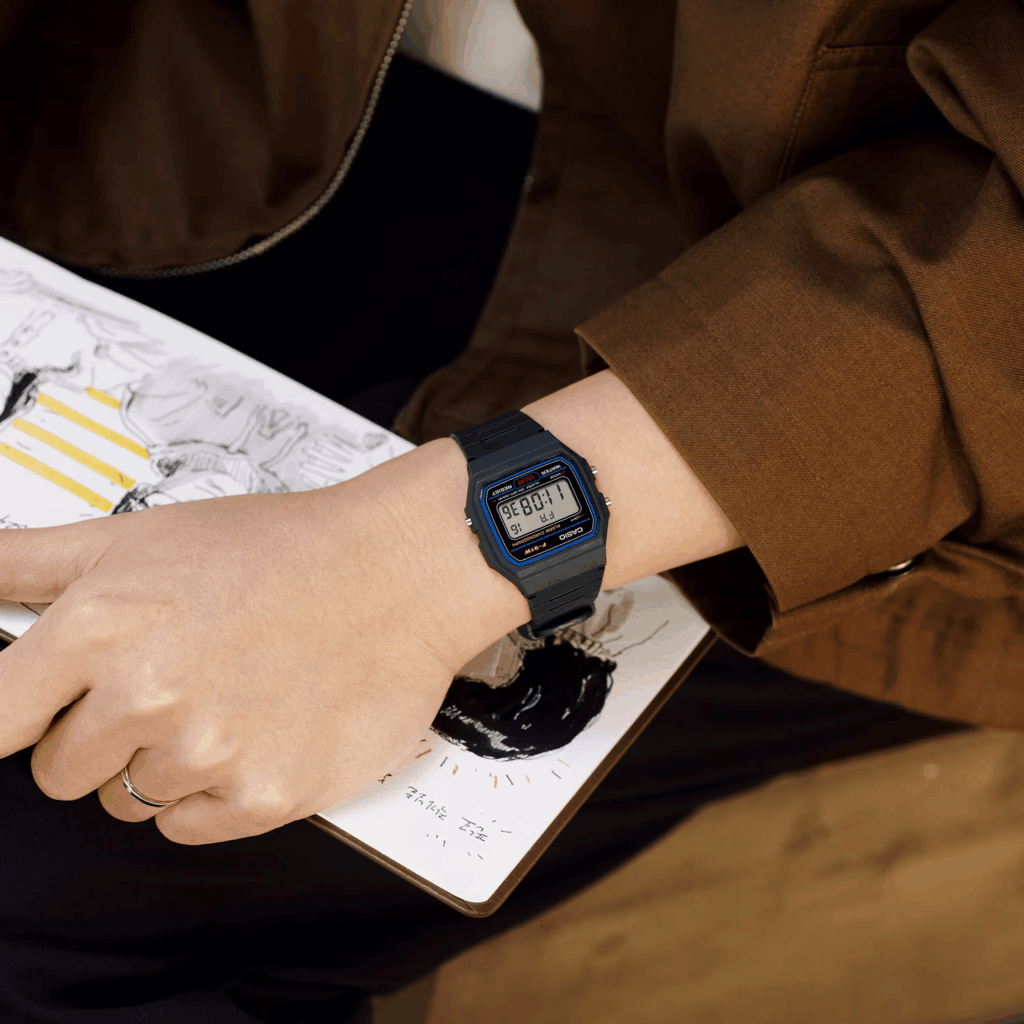 La main d'une personne portant une montre F-91W de la marque Casio en version noire