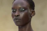 Mannequin au défilé Hodakova à Paris, maquillage graphique argenté et tenue bustier beige