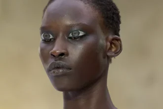 Mannequin au défilé Hodakova à Paris, maquillage graphique argenté et tenue bustier beige