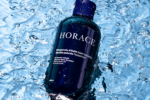 Flacon bleu du gel douche Horace à la bergamote d’Italie et à la menthe poivrée, posé dans l’eau.