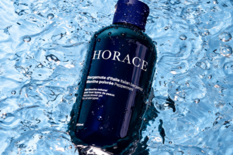 Flacon bleu du gel douche Horace à la bergamote d’Italie et à la menthe poivrée, posé dans l’eau.