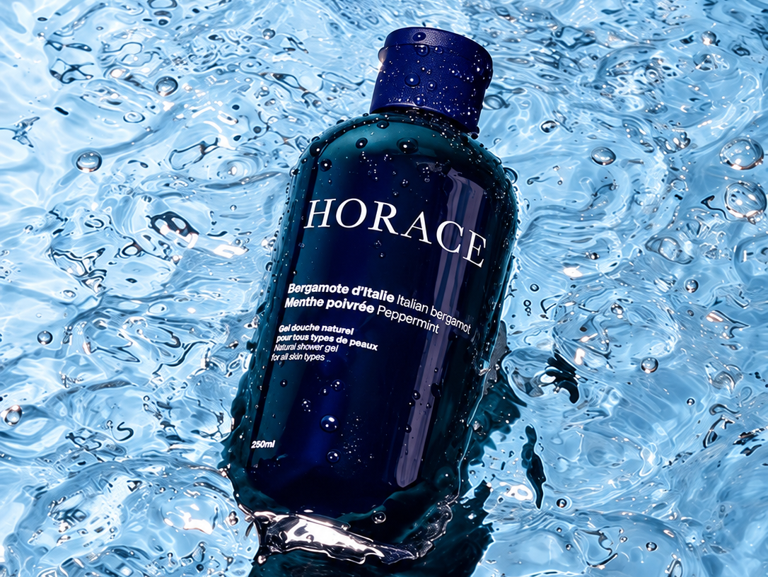 Flacon bleu du gel douche Horace à la bergamote d’Italie et à la menthe poivrée, posé dans l’eau.