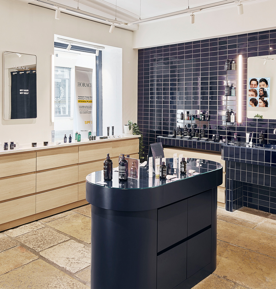 Intérieur de la boutique Horace rue Vieille-du-Temple, avec comptoir central, produits exposés et mur carrelé bleu.