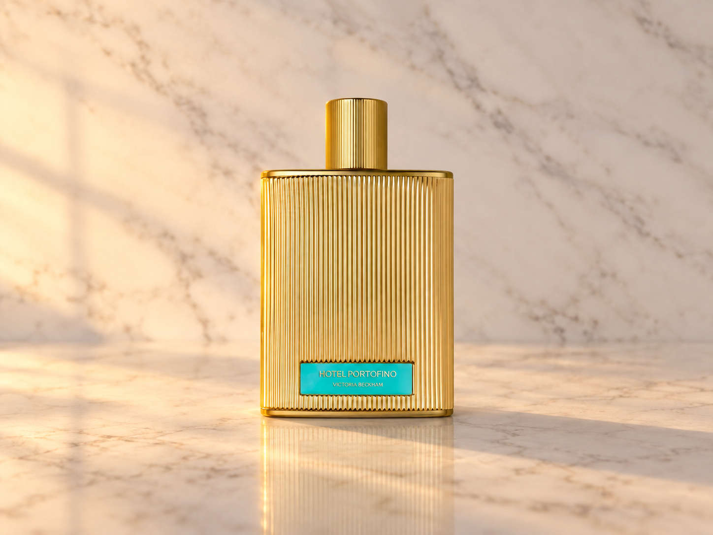 Flacon doré de Hotel Portofino Extrait de Parfum posé sur du marbre blanc sous une lumière chaude