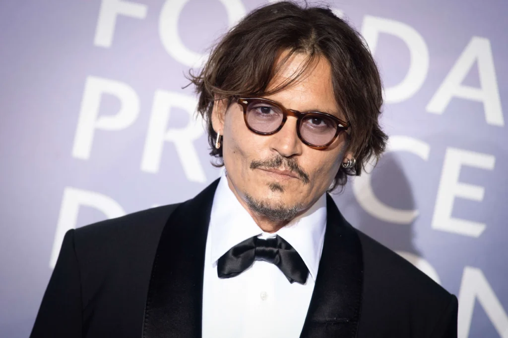 Johnny Depp portant des lunettes à monture brune arrondie avec un smoking et un nœud papillon