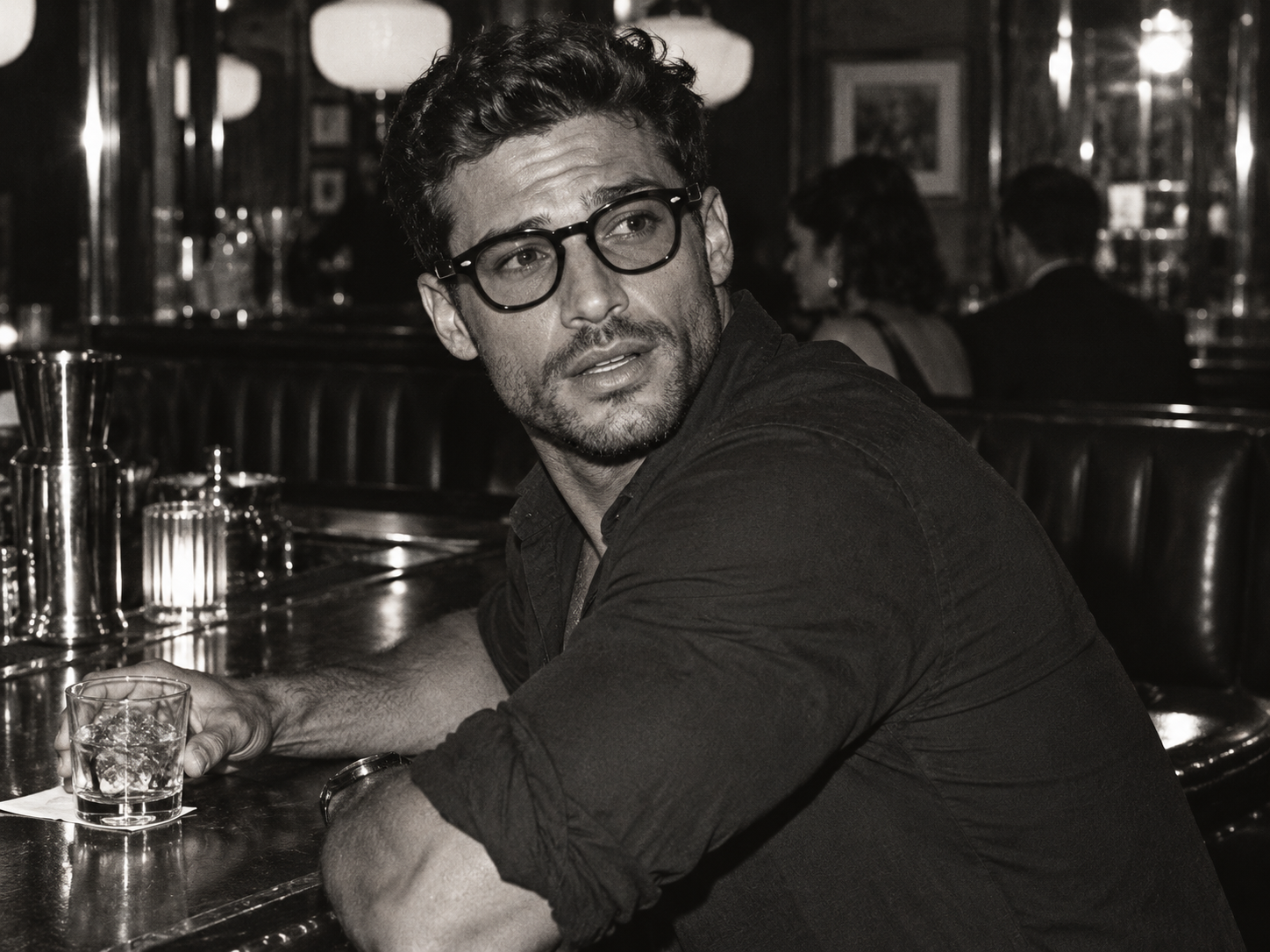 Homme portant une monture noire de style Moscot Lemtosh, assis au comptoir d’un bar Titre : Moscot Lemtosh, lunettes de vue noires