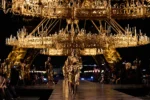 Défilé Saint Laurent printemps-été 2027 à Paris, sous des lustres dorés avec la tour Eiffel en arrière-plan.