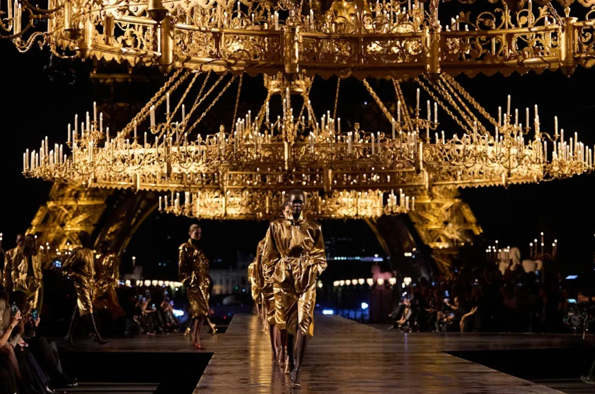 Défilé Saint Laurent printemps-été 2027 à Paris, sous des lustres dorés avec la tour Eiffel en arrière-plan.