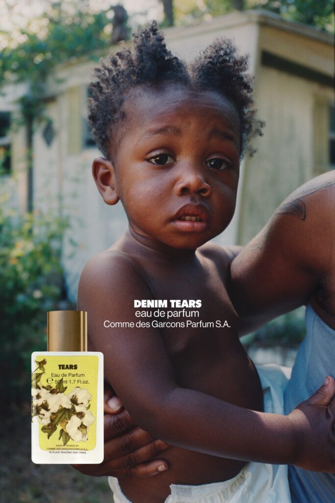 Enfant porté dans les bras d’un adulte sur un visuel publicitaire Denim Tears, avec le flacon du parfum Tears en bas à gauche.