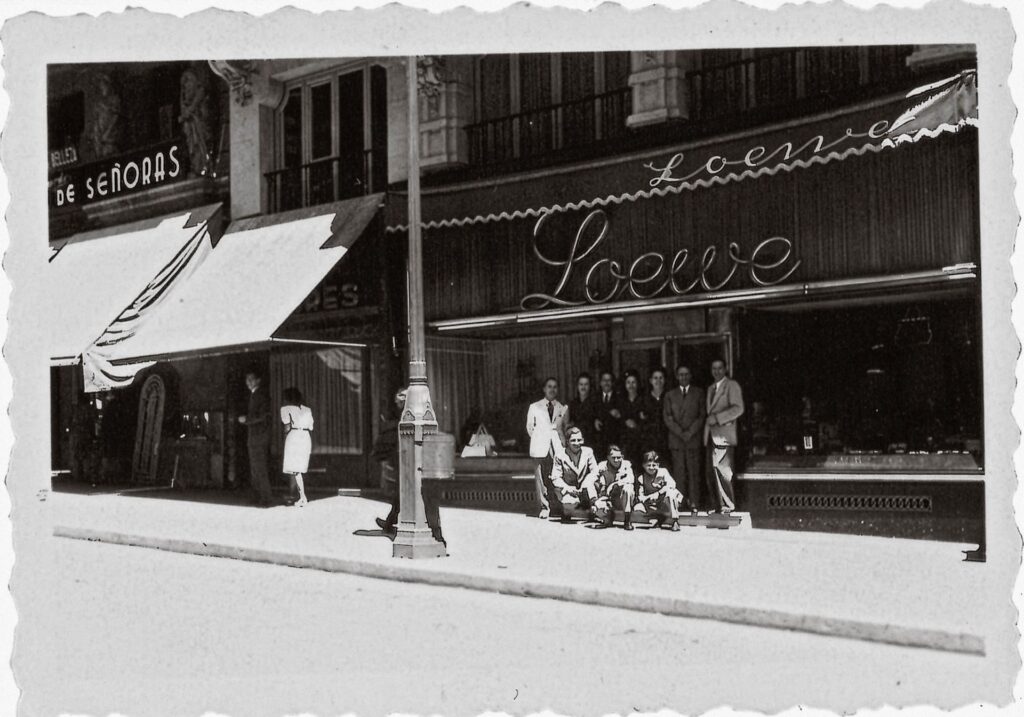 Devanture de la boutique Loewe à Madrid, avec son enseigne et un groupe de personnes posant sur le trottoir.