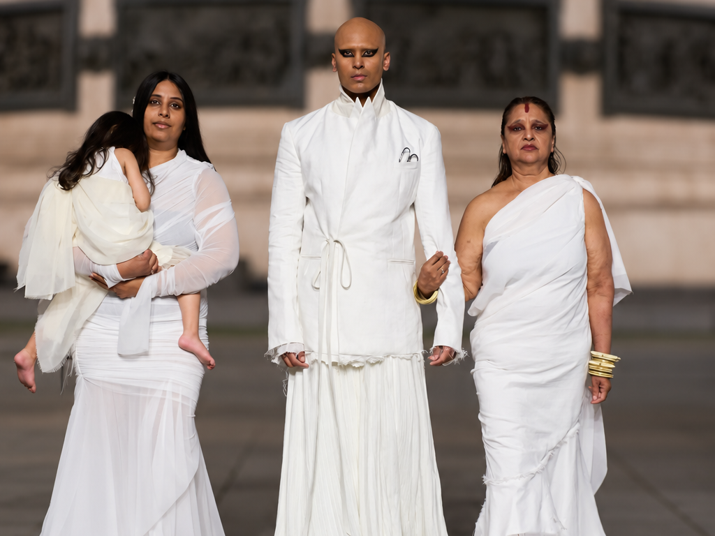Steven Raj Bhaskaran avec sa mère, sa sœur et sa nièce à ses côtés. Vêtues de blanc au défilé Matières Fécales printemps-été 2027 à Paris
