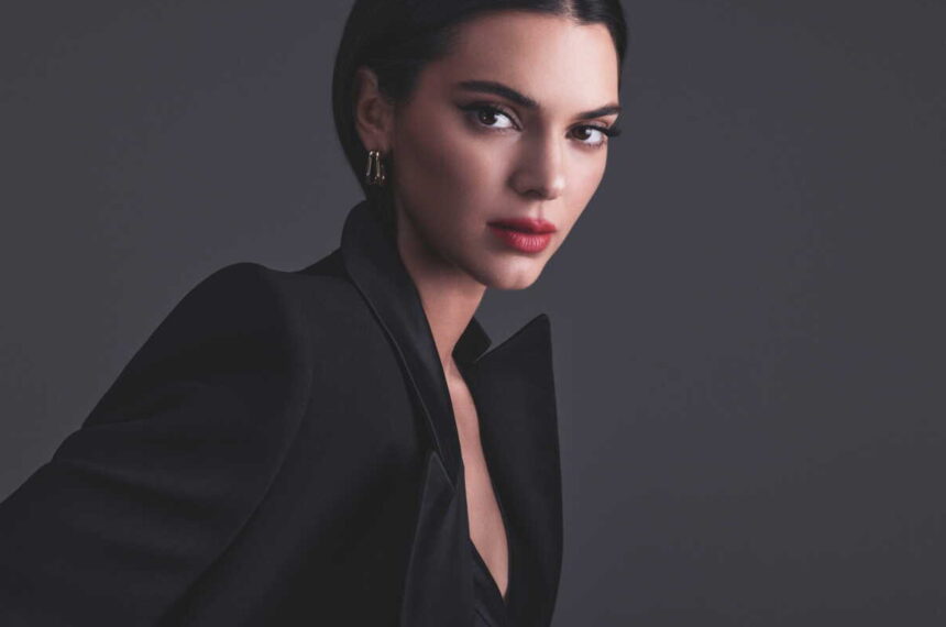 Kendall Jenner en veste noire, photographiée sur fond gris