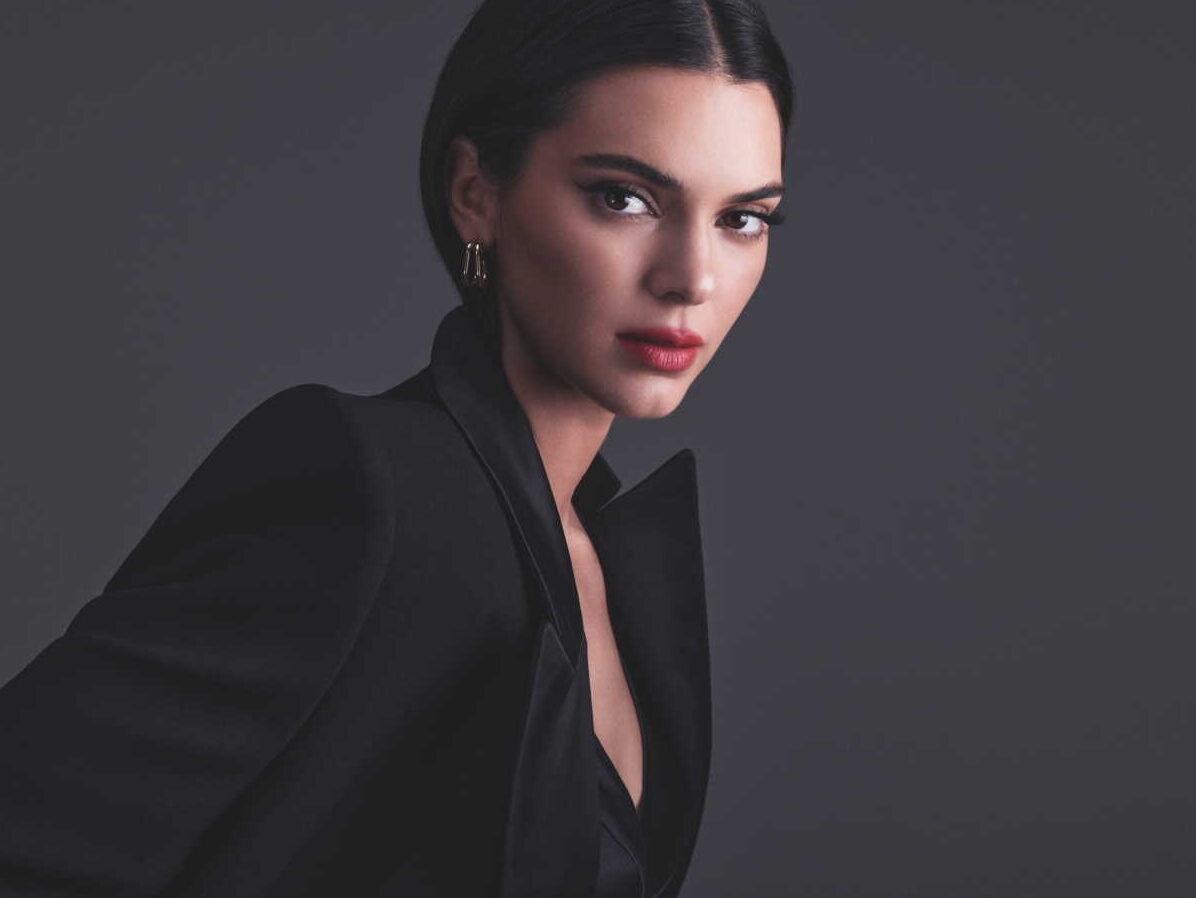 Kendall Jenner en veste noire, photographiée sur fond gris