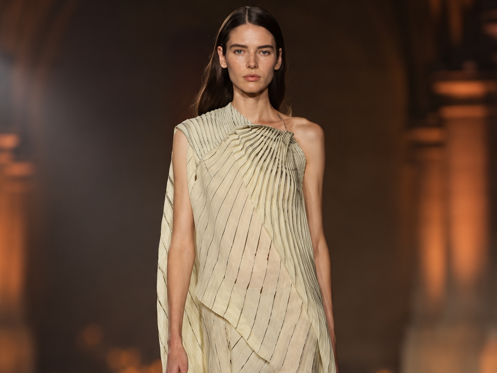 Mannequin portant une robe asymétrique plissée ivoire lors du défilé Victoria Beckham printemps-été 2027 à la Paris Fashion Week.