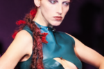 Mannequin aux cheveux roux tressés portant un haut en cuir vert découpé lors du défilé Highland Rape d’Alexander McQueen en 1995.