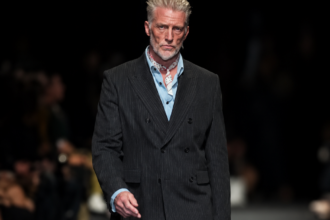 Josh Homme, chanteur de Queens of the Stone Age, défile dans un costume sombre à fines rayures lors du défilé Ann Demeulemeester printemps-été 2027 à Paris.