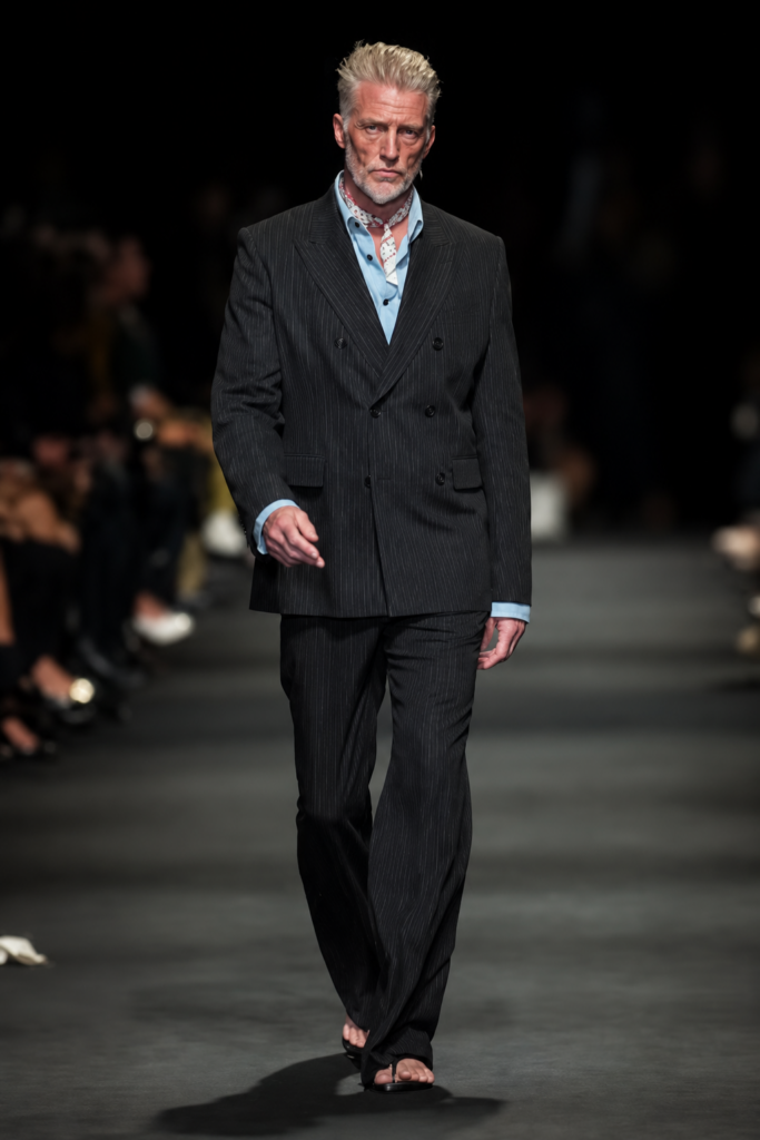 Josh Homme, chanteur de Queens of the Stone Age, défile dans un costume sombre à fines rayures lors du défilé Ann Demeulemeester printemps-été 2027 à Paris.
