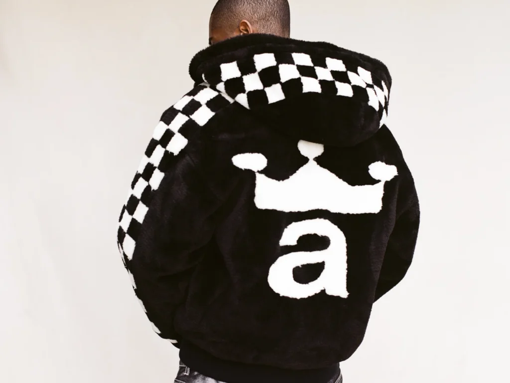 Mannequin de dos portant une veste noire Awake NY à capuche, avec un damier noir et blanc et un grand motif blanc dans le dos.