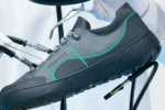 Chaussure Camper Peu Serra grise avec détails verts et semelle noire, présentée dans un décor de laboratoire avec des instruments de précision.
