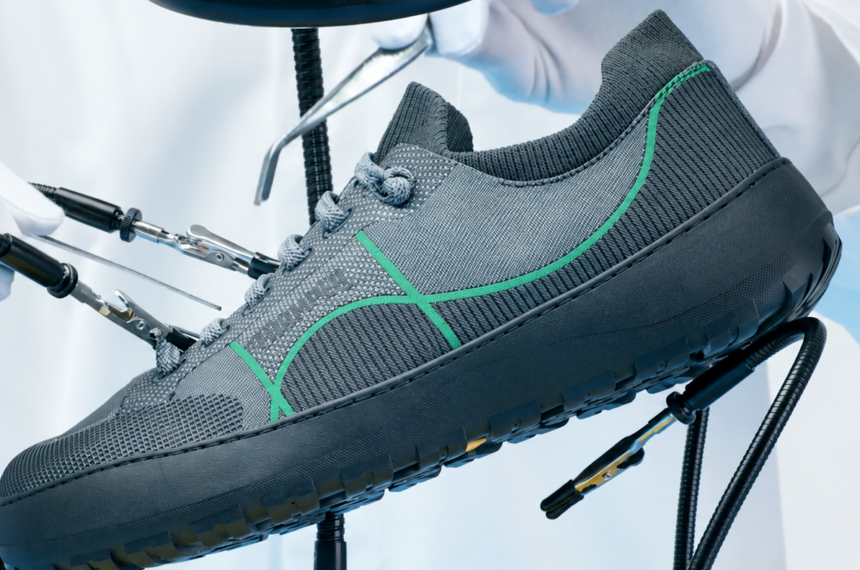 Chaussure Camper Peu Serra grise avec détails verts et semelle noire, présentée dans un décor de laboratoire avec des instruments de précision.