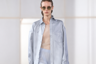 Silhouette Carven printemps-été 2027 à la Paris Fashion Week, avec chemise bleu clair oversize, pantalon transparent et lunettes de soleil.