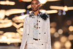 Mannequin portant un tailleur Chanel en tweed blanc à franges noires, composé d'une veste et d'une jupe assortie, lors du défilé printemps-été 2027 à Paris.