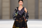 Mannequin en robe imprimée noire et manteau graphique au défilé Dries Van Noten printemps-été 2027 à Paris.