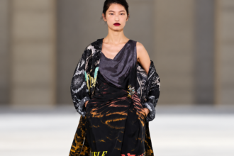 Mannequin en robe imprimée noire et manteau graphique au défilé Dries Van Noten printemps-été 2027 à Paris.
