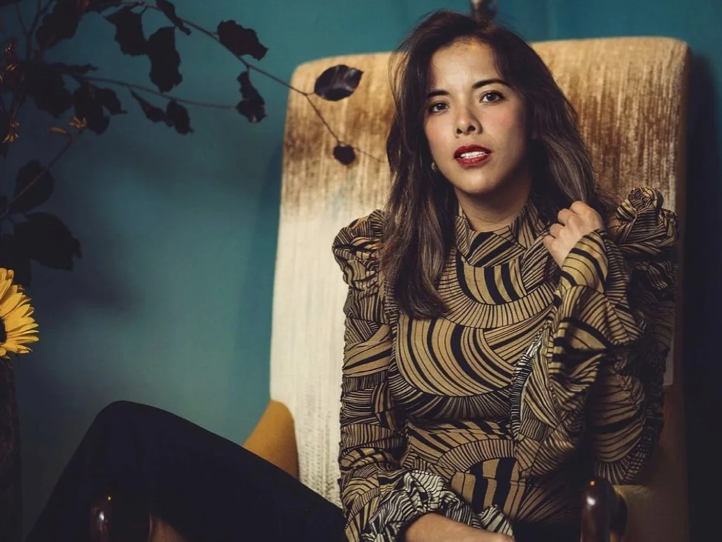 Erika Alvarez, fondatrice de KOUA México, assise dans un fauteuil clair, vêtue d'un haut à motifs géométriques.