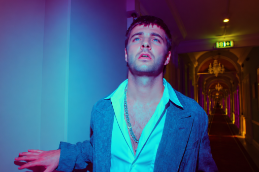 Grian Chatten, chanteur de Fontaines D.C., dans le clip Marianne, extrait de l'album Dopamine Chamber, sous des lumières bleues et violettes.