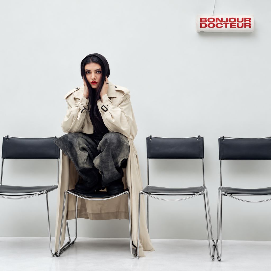 Hoshi assise sur une chaise, vêtue d’un trench beige, dans le visuel de son album Bonjour Docteur.