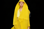 Silhouette jaune ample et drapée du défilé Issey Miyake printemps-été 2027 sur un podium noir.