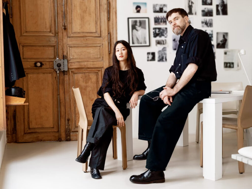 Christophe Lemaire et Sarah-Linh Tran, créateurs de la maison Lemaire, habillés en noir dans un atelier parisien.