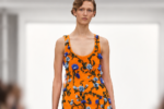Mannequin portant une robe orange brodée de fleurs bleues lors du défilé Loewe printemps-été 2027 à Paris.