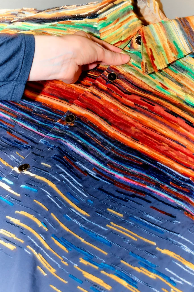 Gros plan sur un costume Chanel de Matthieu Blazy pour Rings of Saturn, aux rayures colorées et boutons noirs.