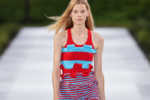 Silhouette rouge et bleu turquoise du défilé Stella McCartney printemps-été 2027 à la Paris Fashion Week, sur fond de podium flouté.